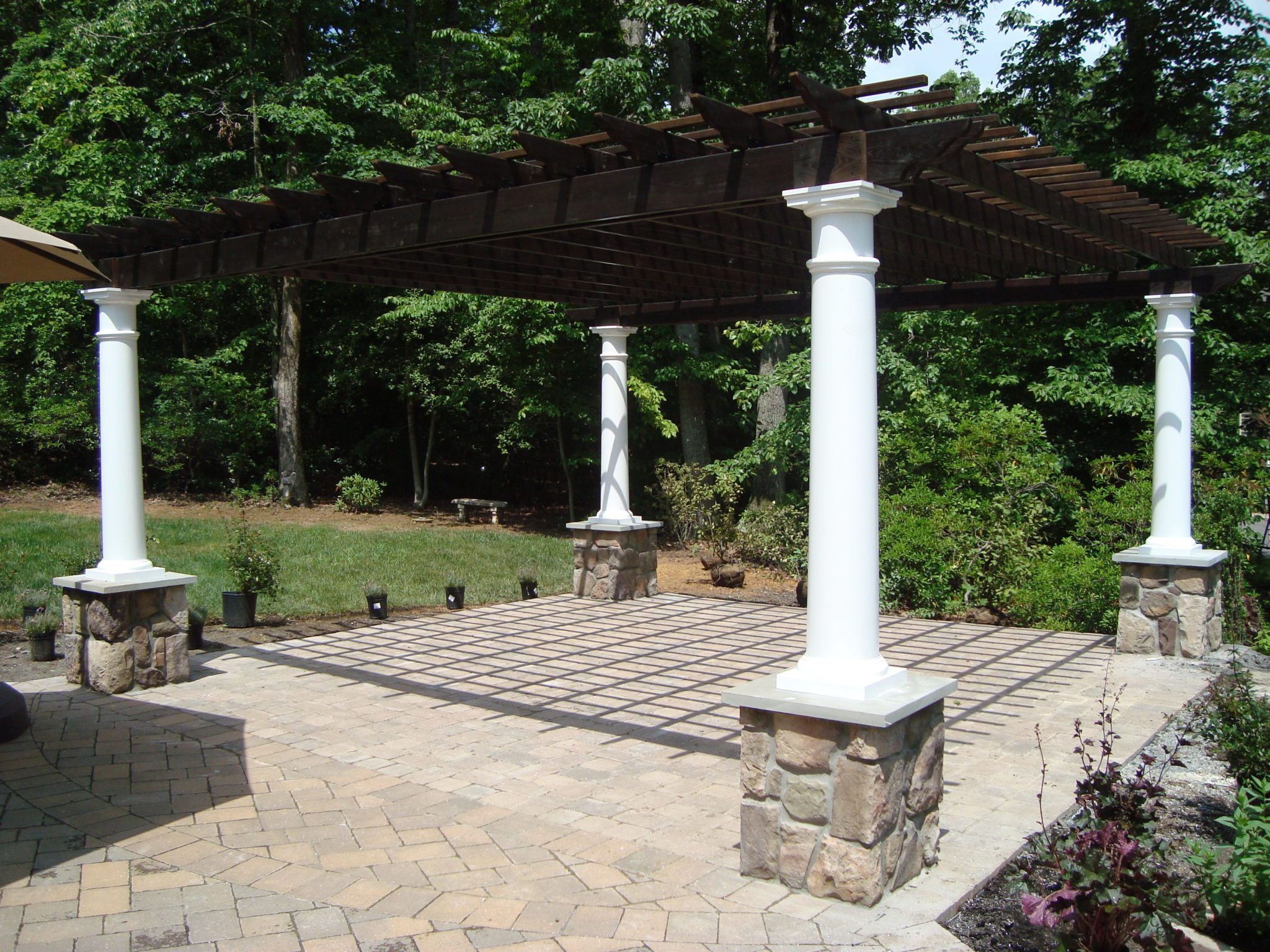 Pergola with cinder stain and white vinyl columns.